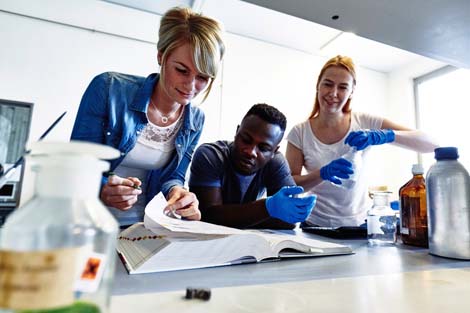 Auf dem Bild sind 3 Studierende in einem Labor zu sehen, die an einem Experiment tüfteln.