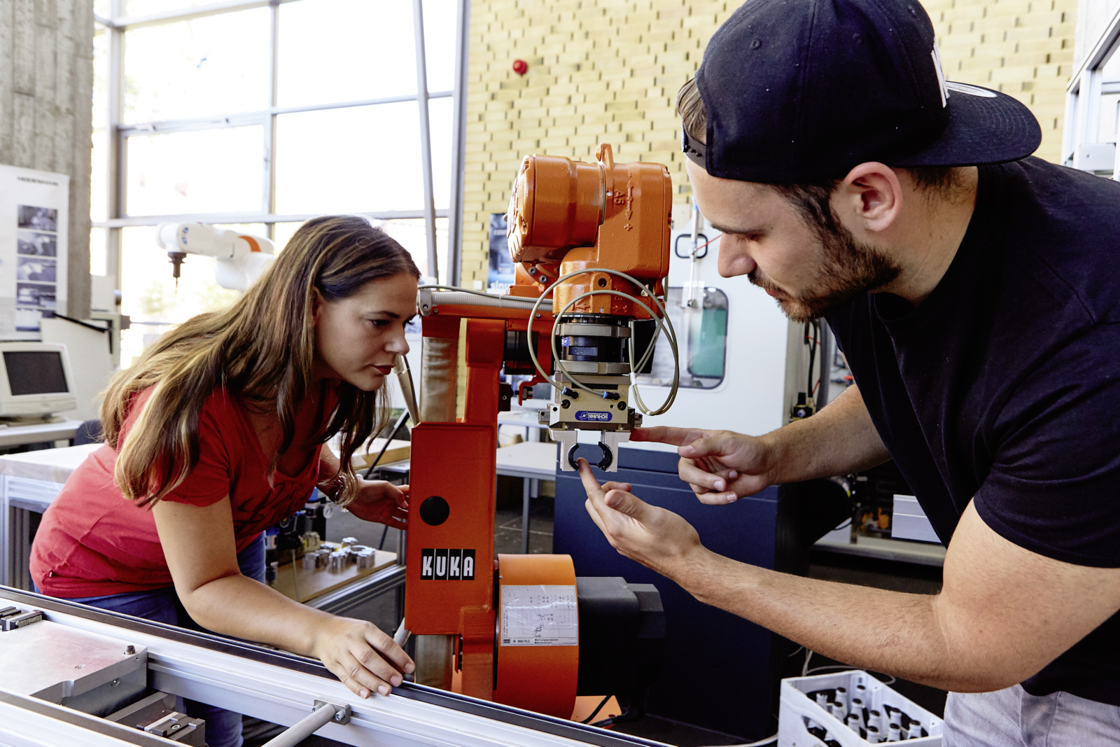Auf dem Bild sind zwei Studierende zu sehen die in einer Maschinenhalle arbeiten.